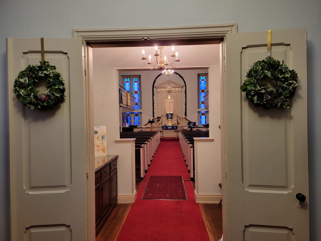 inside view of church aisle decorated with Christmas greens 